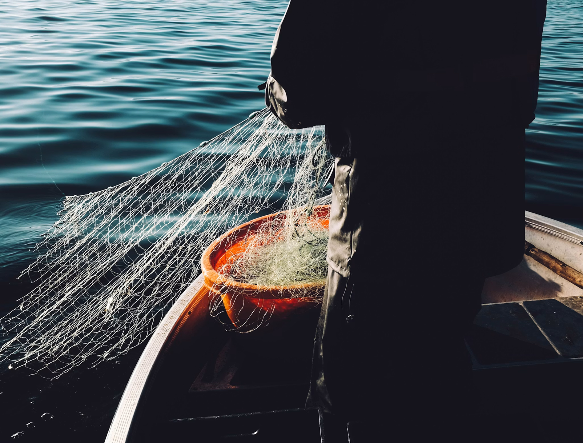 Un pescador recoge su red sobre el agua al amanecer